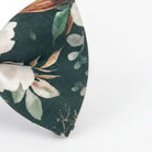 A close-up view of a bow tie with a floral pattern on a dark green fabric.