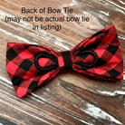 Red and black plaid dog bow tie on a wooden surface.