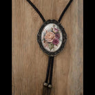 A decorative pendant featuring a floral design, hanging on a wooden surface.