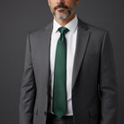 Groomsman wearing a gray suit with an emerald green tie on a dark background