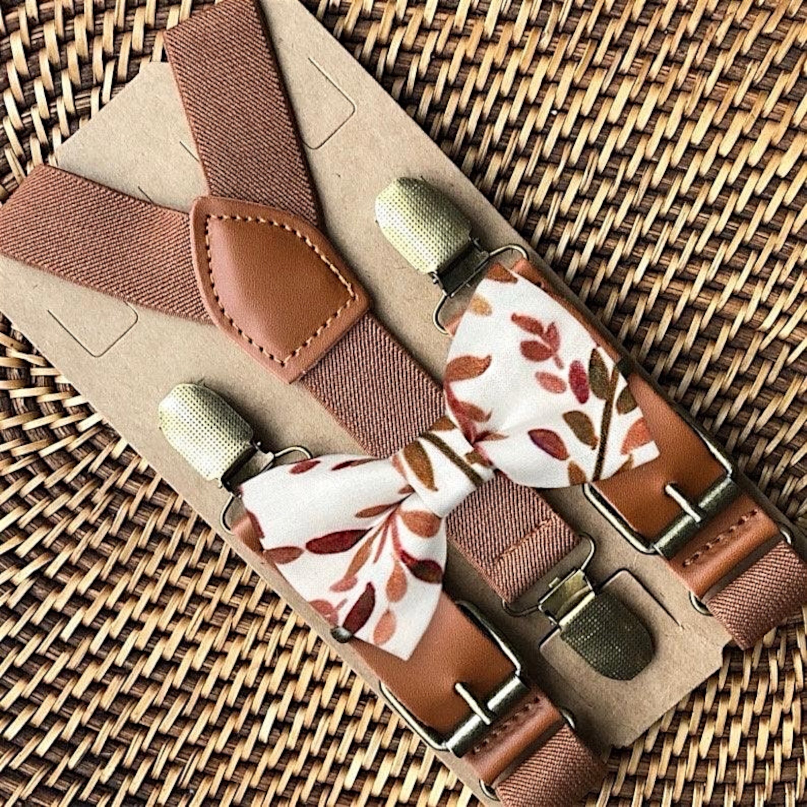 Brown suspenders with terracotta floral patterned clips on a woven surface