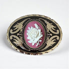 Decorative belt buckle with rose design on a white background