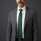 Man wearing a gray suit with an emerald green tie on a dark background