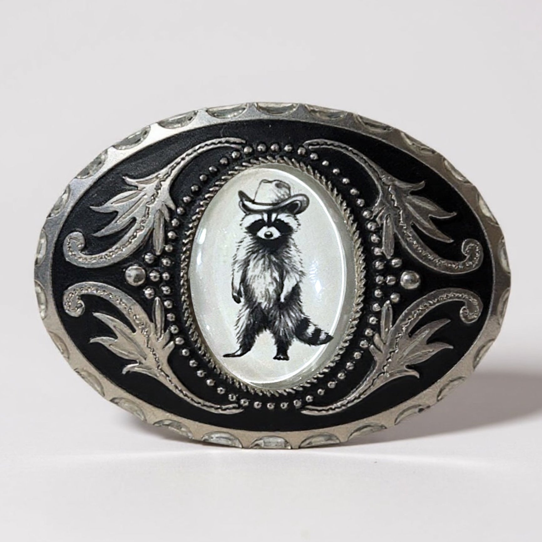 Raccoon Belt buckle with raccoon illustration wearing a cowboy hat on a white background