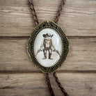Bolo tie with frog cowboy design on a wooden surface