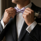 A man in a suit and tie is adjusting his purple bow tie.