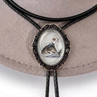 A close-up of a bolo tie with a fish design, featuring a person riding a fish.