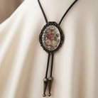 A close-up of a decorative pendant necklace with a floral design on a green velvet background.