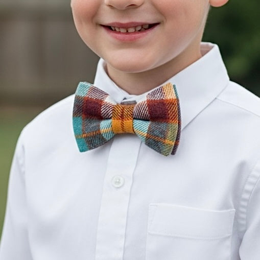 Child wearing a fall plaid bow tie and white shirt with a blurred background