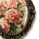 a close-up view of a decorative oval frame with a floral design, including pink roses and green leaves.