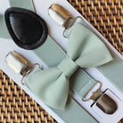 Sage green bow tie and sage green suspenders for a wedding displayed on a woven tray by The Bold Bow Tie.