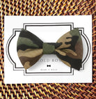 A camouflage bow tie is displayed on a white card with a black border, accompanied by the text "BOLD BOWL WEAR IT BOLD".