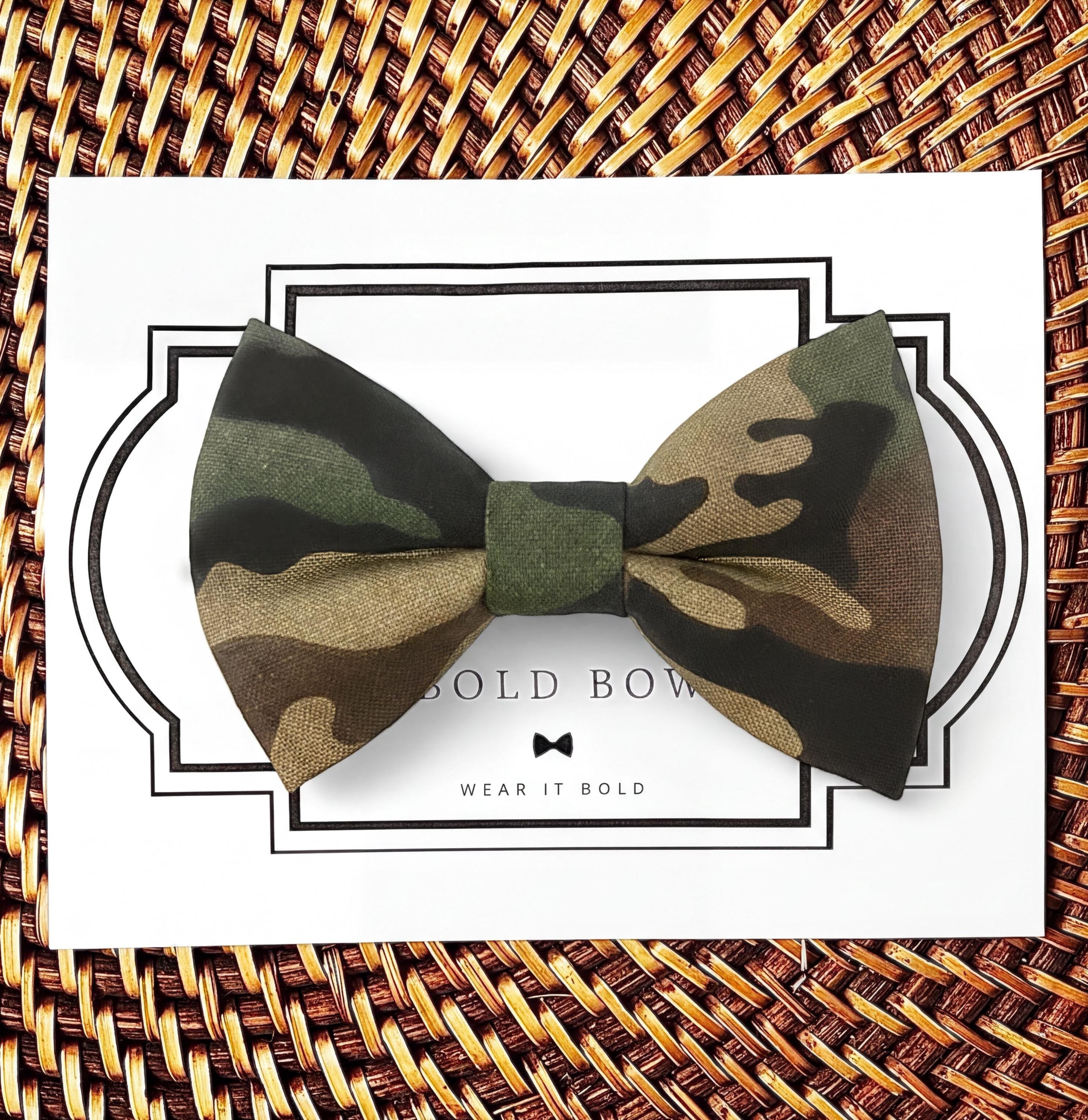 A camouflage bow tie is displayed on a white card with a black border, accompanied by the text "BOLD BOWL WEAR IT BOLD".