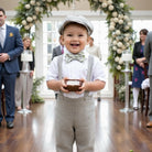 Ring bearer in a dinosaur bow tie holding a small box walking down the aisle at a wedding.