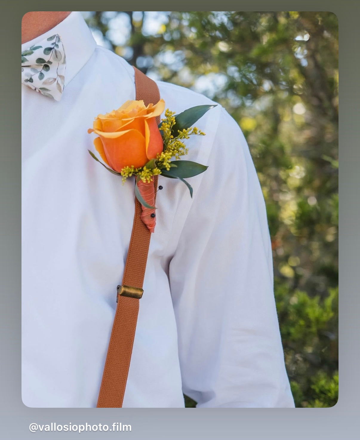 Sage floral bow tie and brown suspenders worn by a groomsman at a wedding.