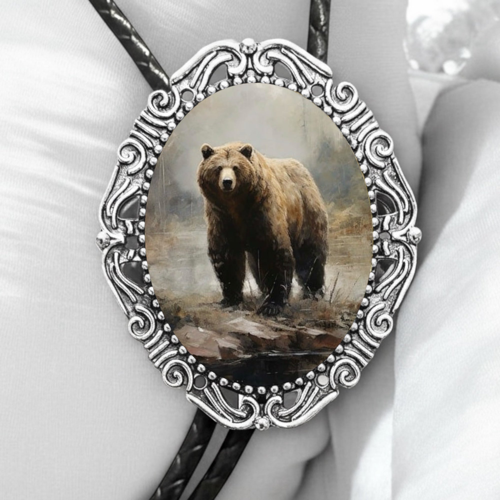 Bolo tie with a bear design in an ornate silver frame on a white background