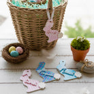 Decorative Easter name tags with pastel colors on a wooden surface with a basket and nest.