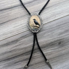 Bolo tie with raven pendant on a wooden surface