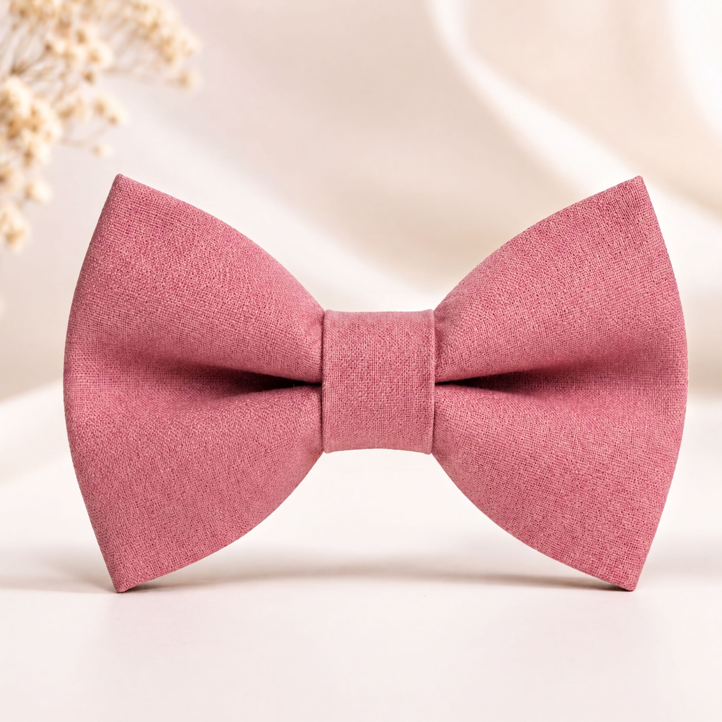 Blush pink dusty rose bow tie, formal wedding accessory for men, symmetrical pre-tied design on soft neutral background