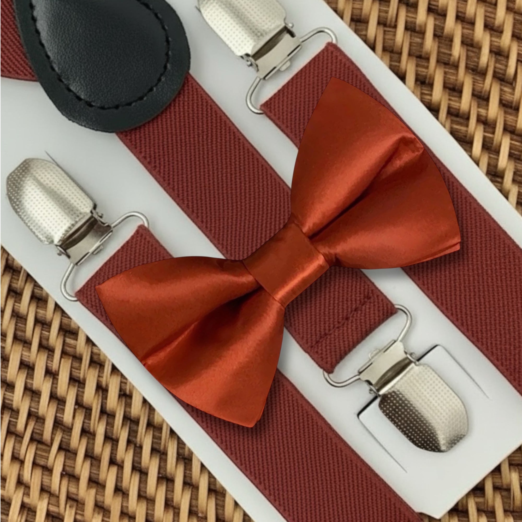 Burnt orange bowtie with suspenders and clips on a white background