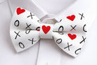 White Valentines Day bow tie with red hearts and black 'XO' pattern on a white shirt background