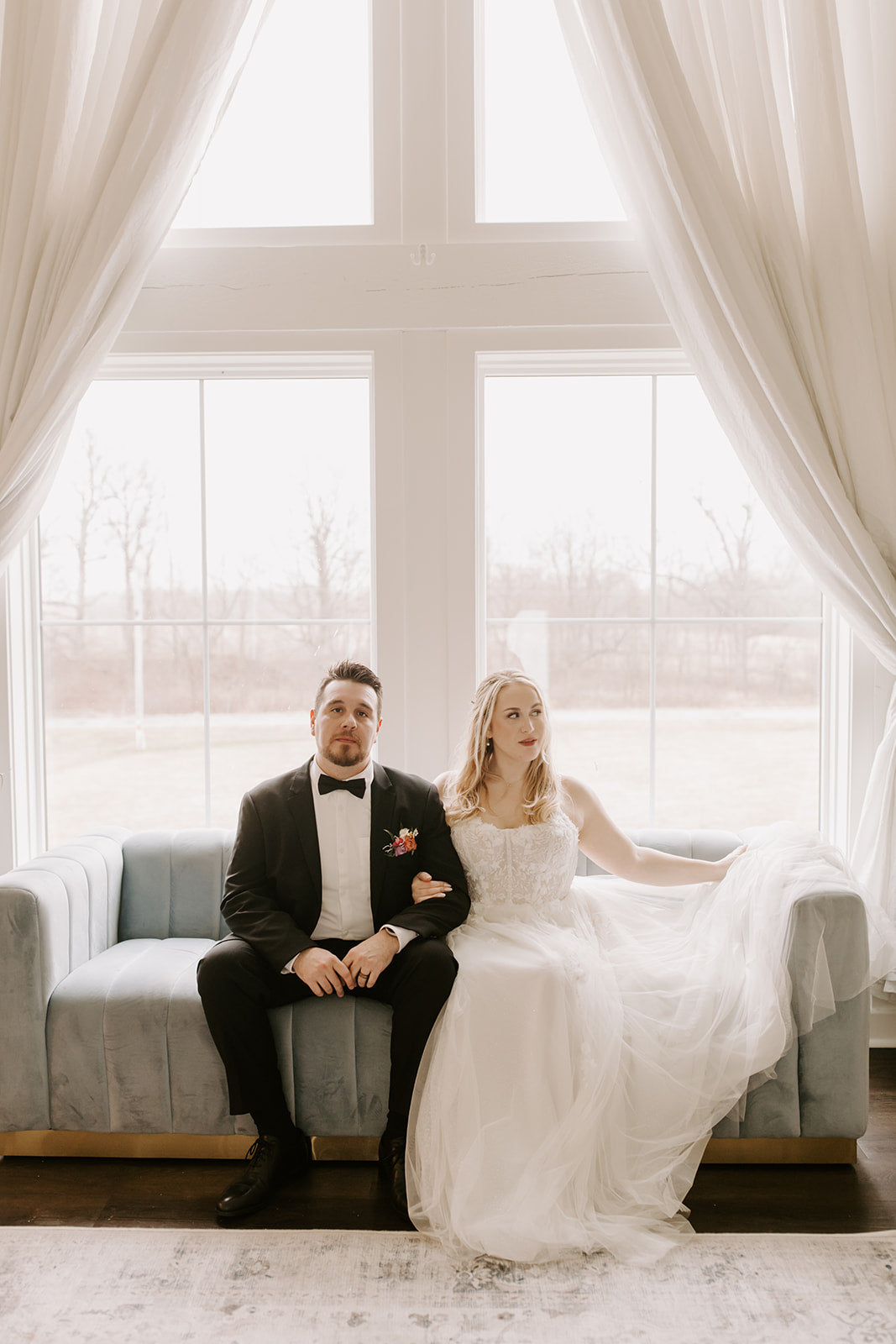 A groom wearing a satin black bow tie sitting next to his bride.