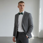 Man wearing a gray suit with a green bow tie for a wedding.