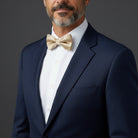 Groomsman wearing a navy suit with a white shirt and champagne bow tie getting ready for a wedding.