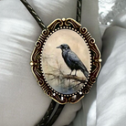 Raven bolo tie and black leather cord on white pillow