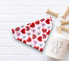 Valentine's Day dog bandana with hearts and a 'Good Dog' mug on a white surface.