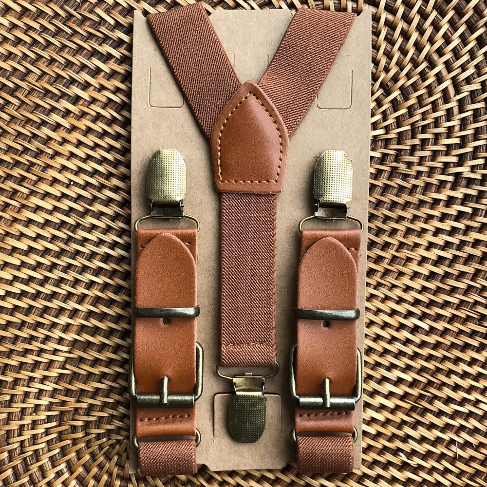 Men’s suspenders with gold clips in a cardboard packaging on a woven surface