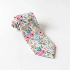 Floral tie for men for wedding groomsman accessory rolled up on a white table.