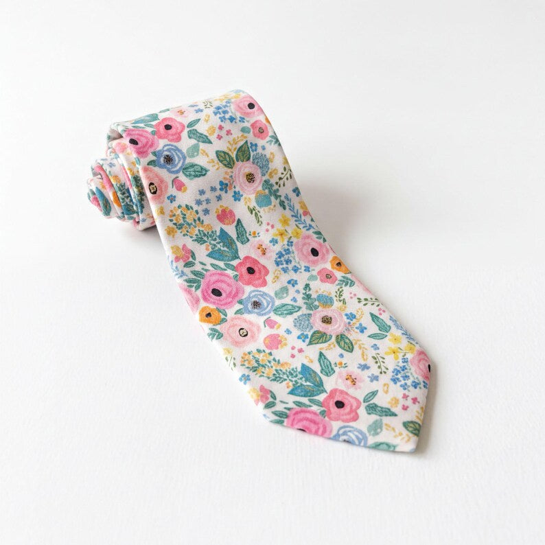 Floral tie for men for wedding groomsman accessory rolled up on a white table.