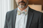 Groomsman in a gray suit with floral bow tie.