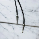 Silver bolo tassels on a black leather cord 