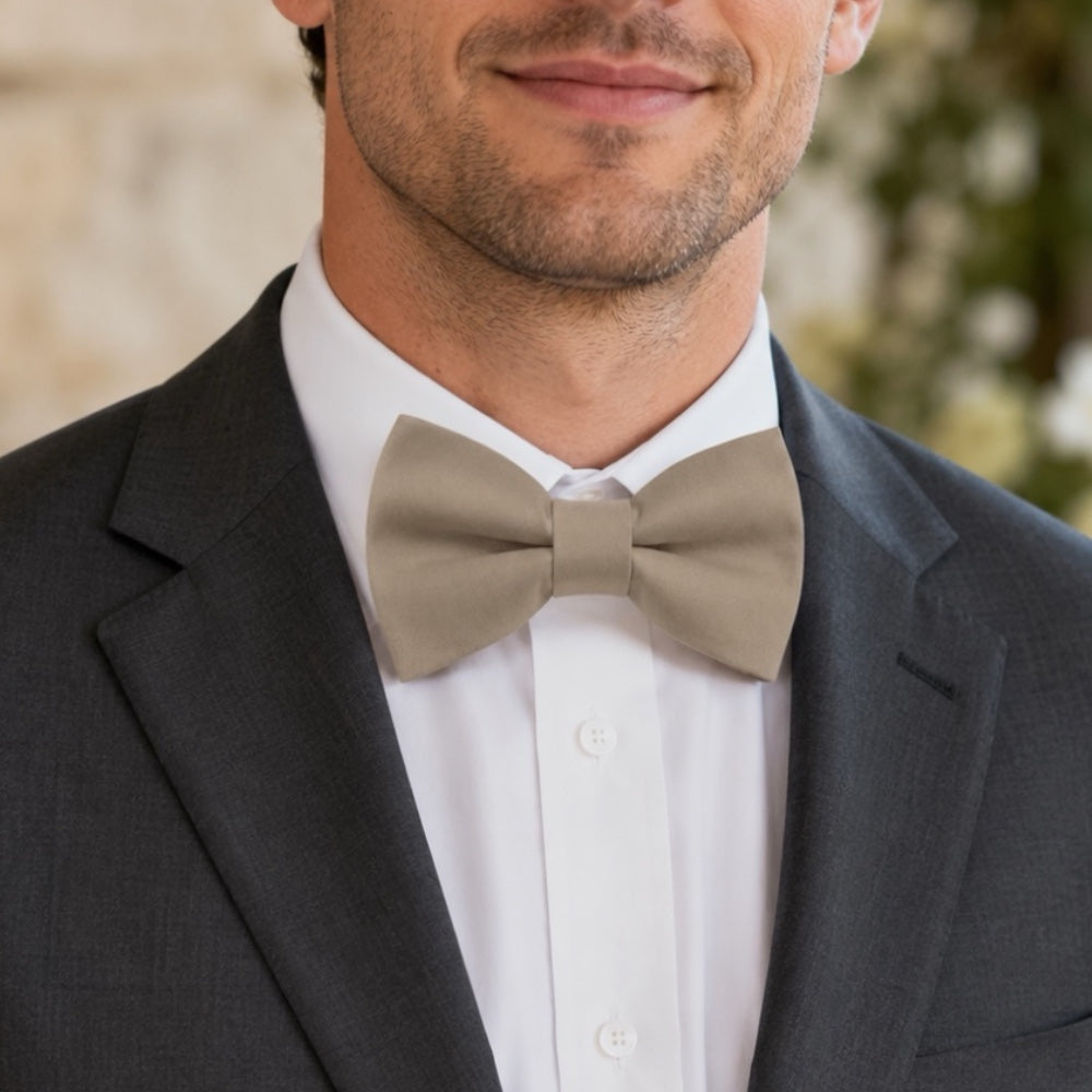 Close up of a groomsman in a taupe bow tie and suit for a wedding outfit.
