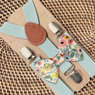 Floral groomsman bow tie and suspenders set on a woven surface