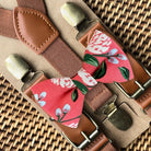 Pink floral bow tie and suspenders set on a woven surface