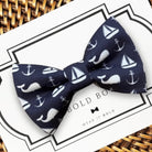 Navy blue dog bow tie with white sailboat and anchor pattern on a Bold Bow branded card.