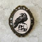 Decorative Raven brooch with a black bird and skull design on a marble background