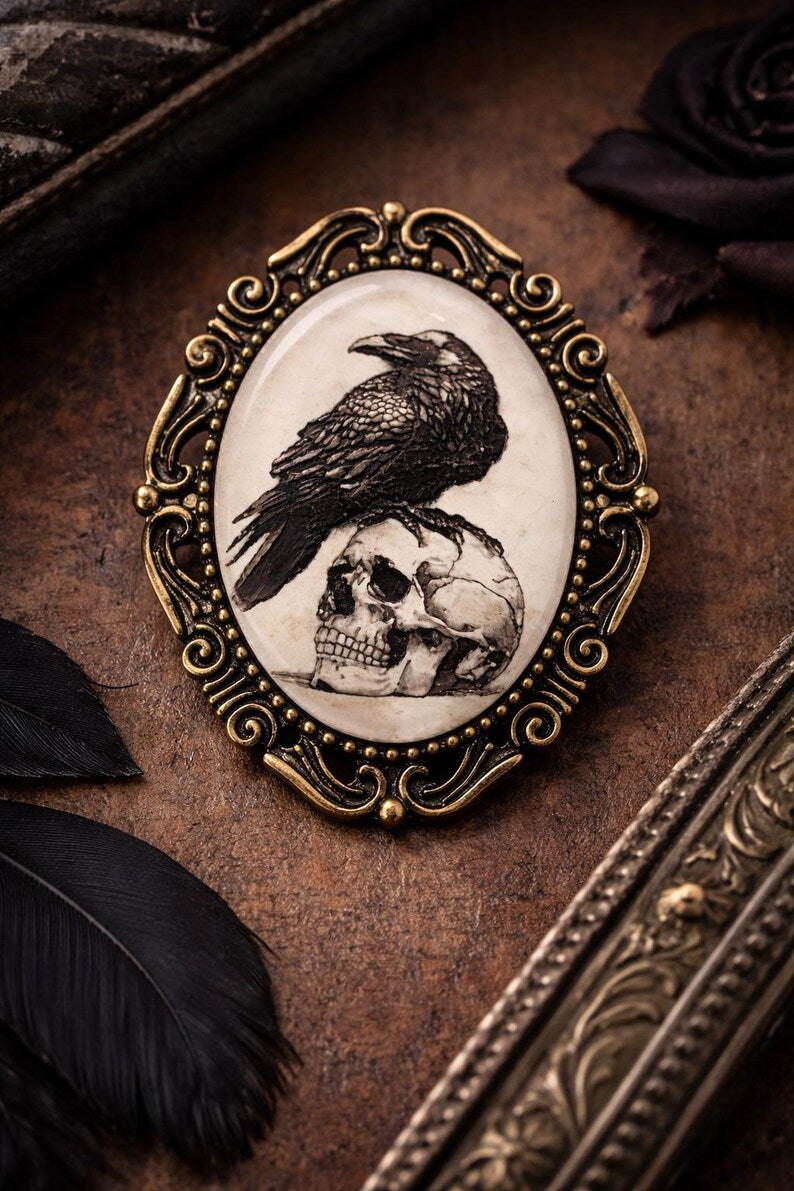 Decorative black bird brooch with a raven and skull design on a textured surface.