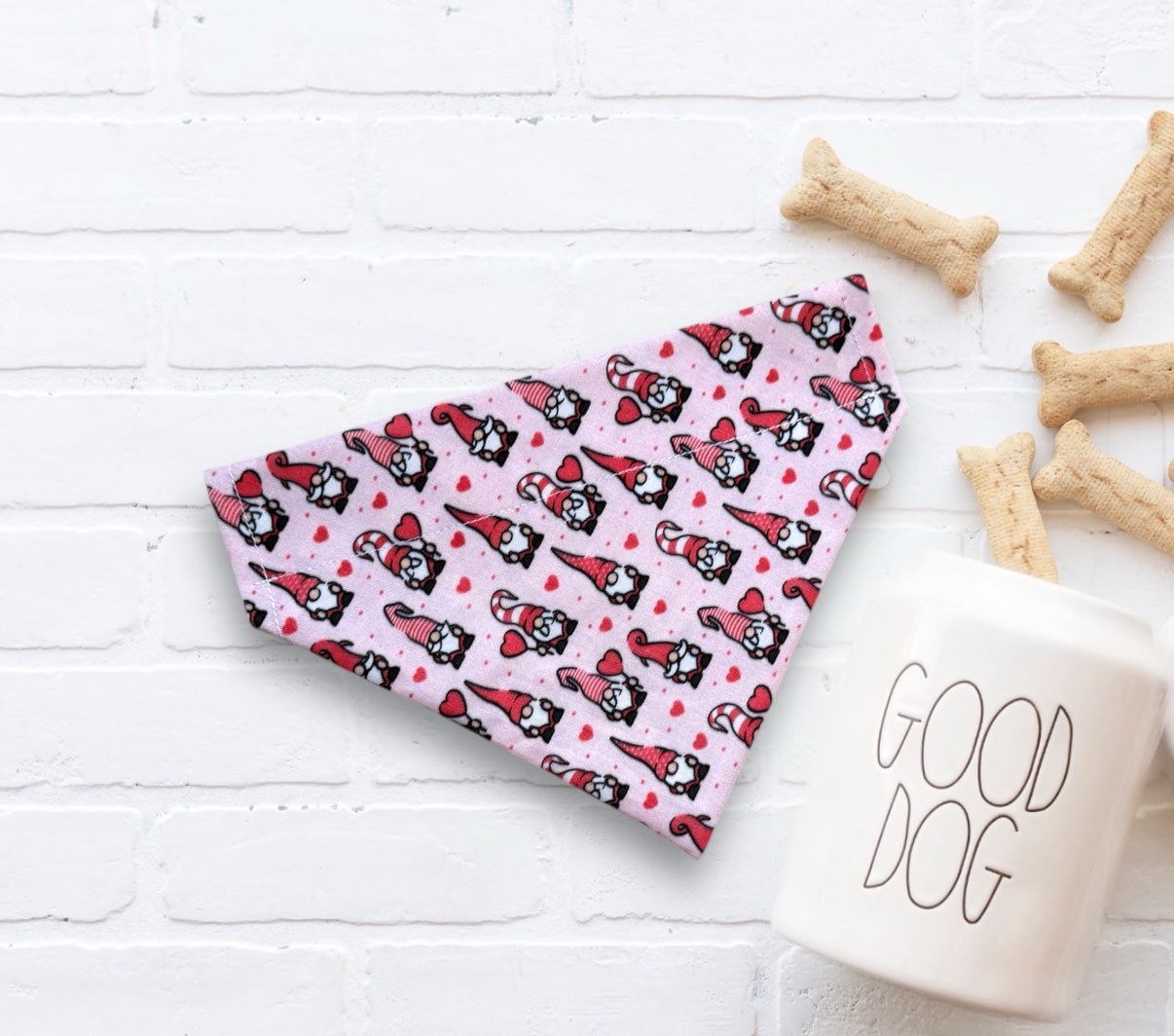 Valentines Day dog bandana with gnomes on a white surface with dog treats and a 'Good Dog' mug.