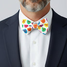 Man wearing a Valentines Day bow tie with heart-shaped designs on a plain background