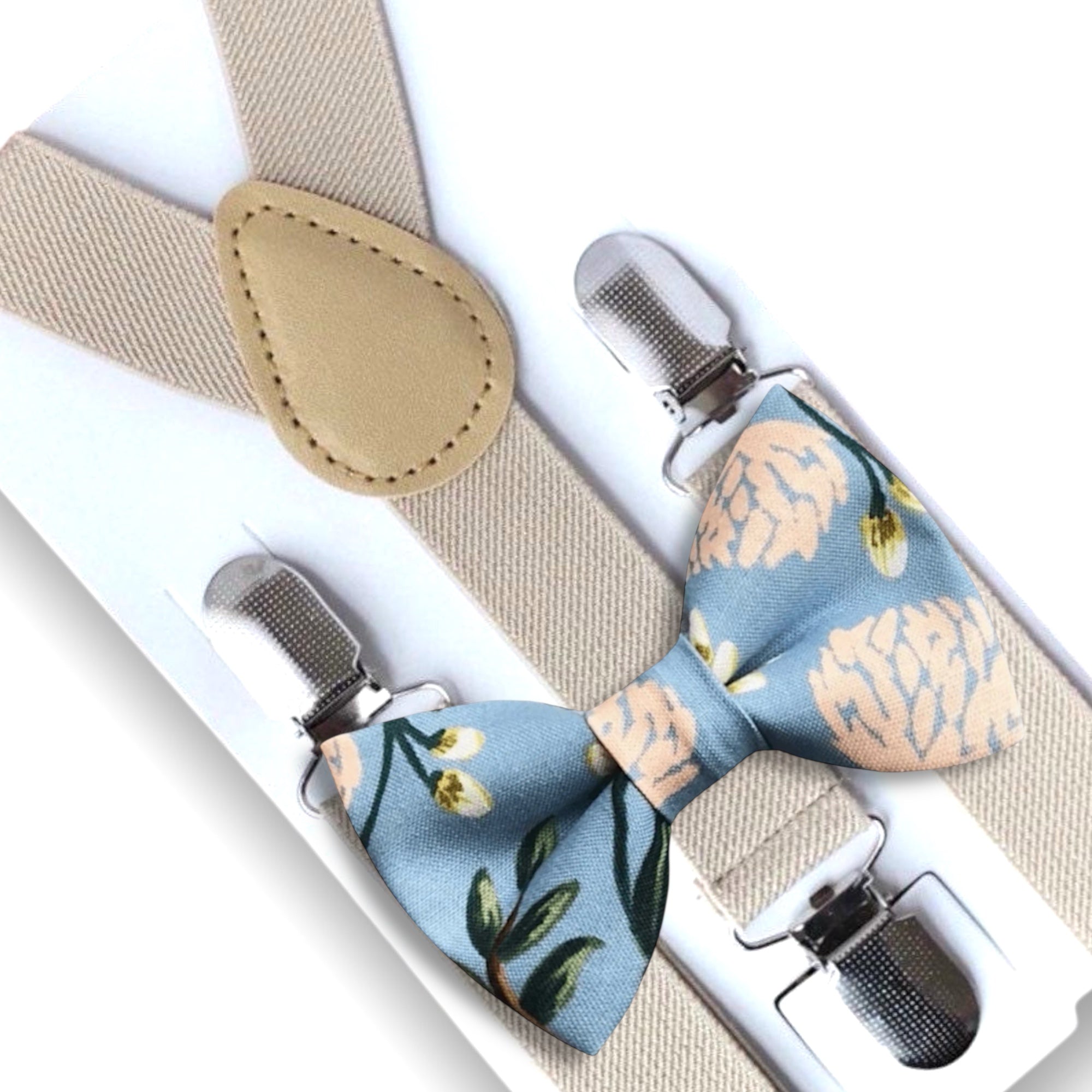 Dusty blue floral bow tie and tan suspenders set on a white background made in the USA by a woman owned company.
