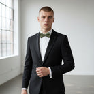 Groomsman wearing a black tuxedo with an olive green bow tie for a wedding.
