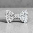 White Easter toddler bow tie with gray pattern on a gray surface.