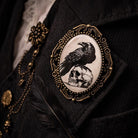 Decorative brooch with a raven and skull design on a dark background