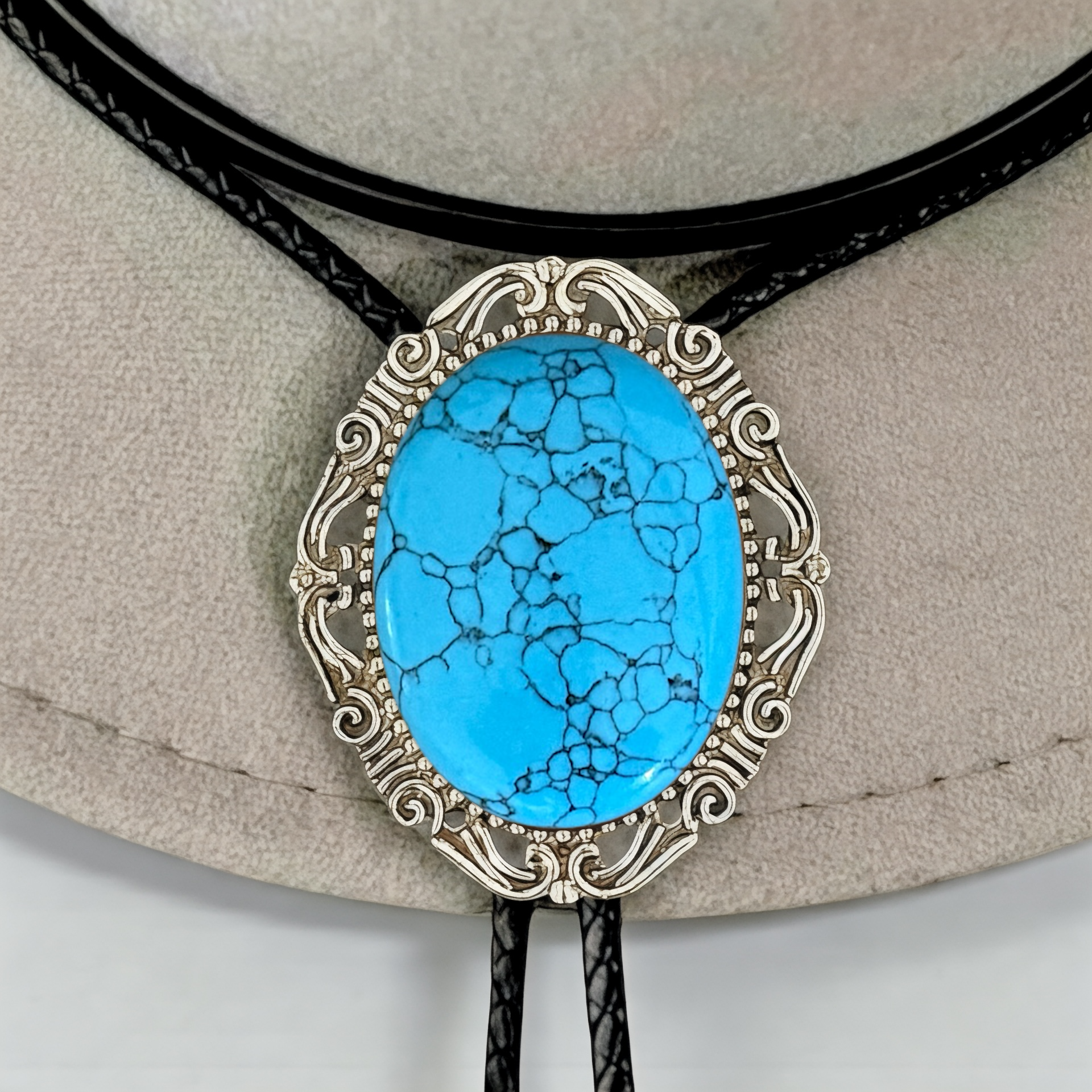 Dark Turquoise bolo tie with silver frame on a beige background