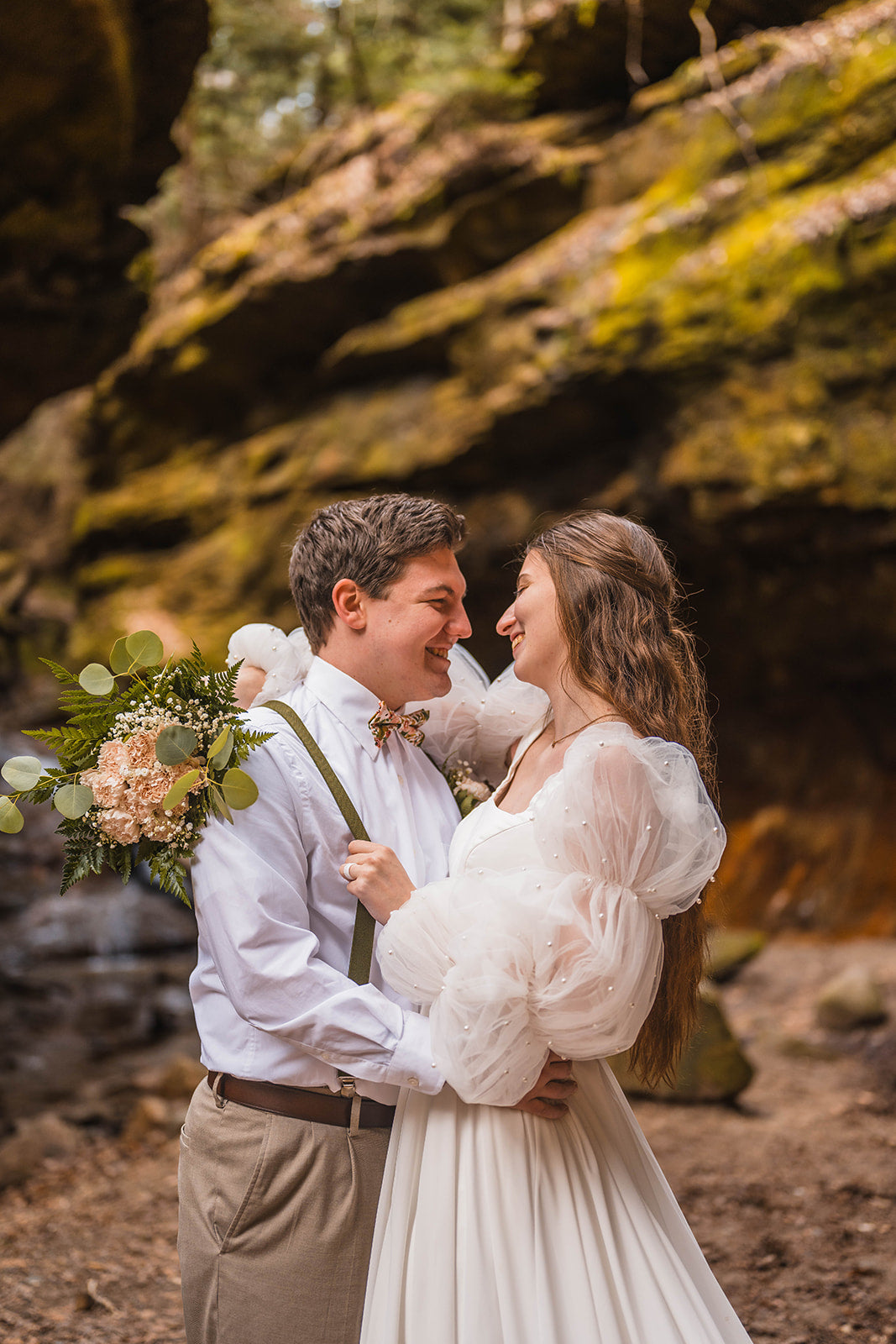 Bride and groom smiling and embracing in a rustic wedding setting.