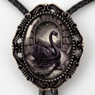 A decorative pendant featuring a black swan swimming in a pond, surrounded by books and a starry sky.